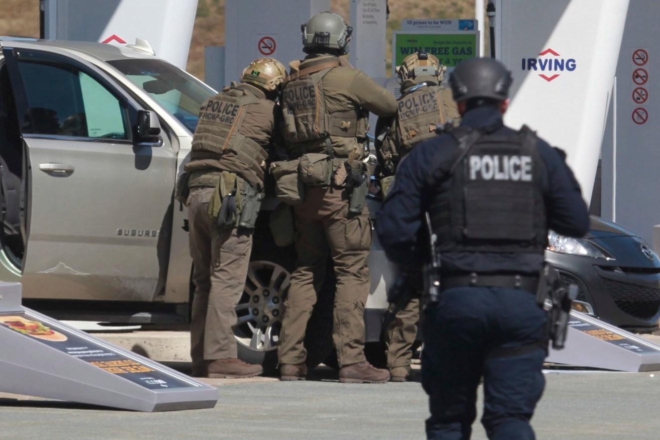 Royal Canadian Mounted Police officers prepare to take a suspect into custody at a gas station in Enfield, Nova Scotia on Sunday April 19, 2020. (Tim Krochak/The Canadian Press via AP)