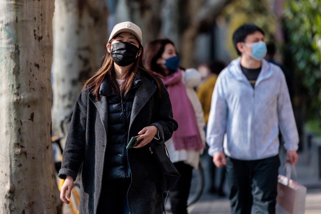 People wearing masks walk around Shanghai. (EPA/ALEX PLAVEVSKI)